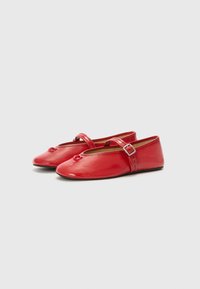 Red patent leather ballet flats with a rounded toe, flat sole, and a decorative strap with a buckle. Textured surface and bow detail.