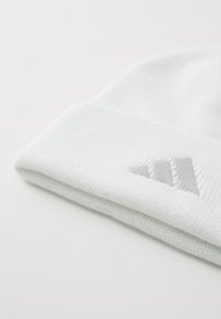 Light blue knit beanie with a folded cuff, featuring a gray embroidered logo in the shape of three parallel stripes. Soft texture.