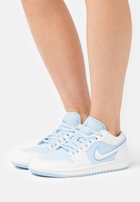 Baskets Nike bleu et blanc avec tige en cuir, bout perforé et lacets plats, semelle en caoutchouc et détail signature Swoosh.