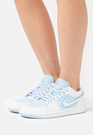 Baskets Nike bleu et blanc avec tige en cuir, bout perforé et lacets plats, semelle en caoutchouc et détail signature Swoosh.