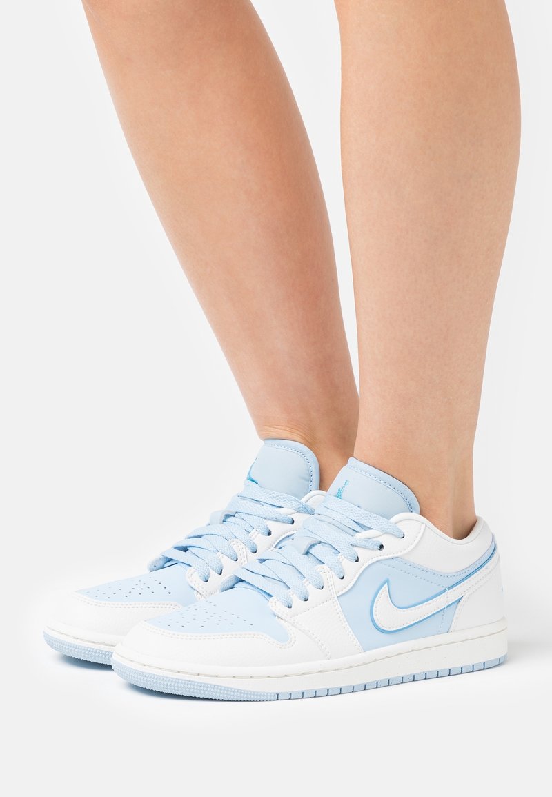 Baskets Nike bleu et blanc avec tige en cuir, bout perforé et lacets plats, semelle en caoutchouc et détail signature Swoosh.