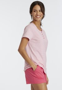 Striped pink T-shirt with short sleeves and button detail, paired with solid pink shorts. The fabric appears soft and lightweight.