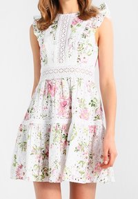 Weißes Kleid mit floralem Muster in Rosa und Grün. Verfügt über Rüschensäume, Spitzenverzierungen und ein gestuftes Rockdesign.