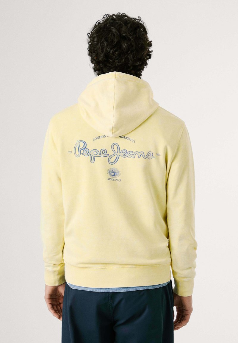 Gelber Kapuzenpullover mit Kordelzug, auf der Rückseite mit einem blauen "Pepe Jeans"-Logo. Weiche Textur, lange Ärmel und gerippte Bündchen.