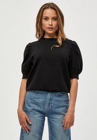 Svart puffärmad topp i mjukt tyg som har rund halsringning, avslappnad passform och slät yta, i kombination med ljusblå jeans med hög midja.