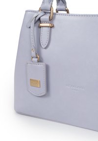 Borsa a tracolla di pelle lilla con accessori in oro, dotata di un'etichetta attaccata e logo impresso. Texture liscia e design strutturato.