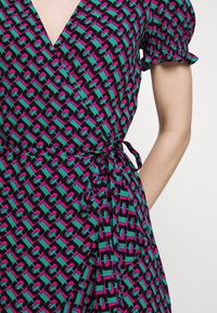 Vestito a portafoglio con scollo a V e maniche a palloncino annodate in vita, caratterizzato da un motivo geometrico a catena in turchese, rosa e nero.