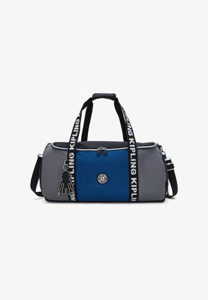 Bolsa de deporte gris y azul con una parte superior negra, que cuenta con una correa negra con el logo "Kipling", un parche circular con el logo y un llavero con un monito como acento.