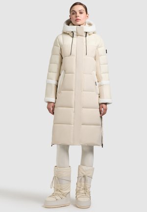 Beige puffer coat with a long design, featuring a fur-lined hood, elastic cuffs, and side pockets; paired with beige fur-lined boots.