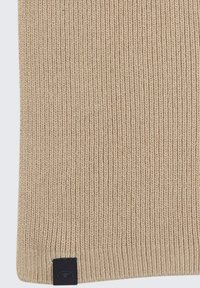Tissu tricoté beige avec une texture côtelée, présentant une étiquette noire en bas. Met l'accent sur une apparence simple et uniforme.