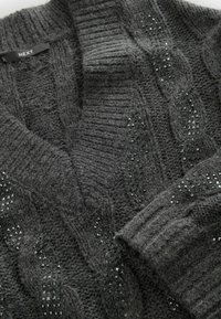 Grå strikket sweater med kabelmønster og små sorte perleaccenter. Har en dyb v-halsudskæring og ribbestrikkede manchetter for tekstur og varme.