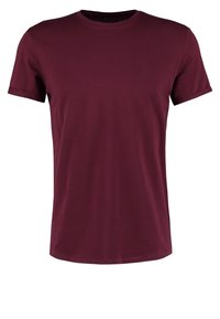 Camiseta de algodón burdeos de manga corta, con cuello redondo y una textura suave. Diseño sencillo sin patrones ni herrajes visibles.