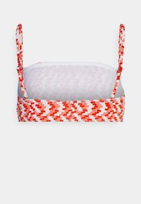 Sutiã com padrão abstrato em vermelho e rosa, tecido suave, alças ajustáveis e design sem costura; possui um forro interior branco.