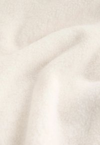 Tissu en polaire blanc avec une surface douce et texturée, présentant de légères plis et rides, mettant en valeur son apparence malléable et confortable.