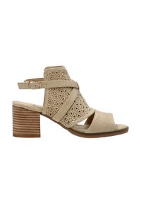 Sandalia de ante beige con tira en el tobillo, patrón floral recortado, punta abierta y un tacón bloque de altura media texturizado con rayas horizontales.