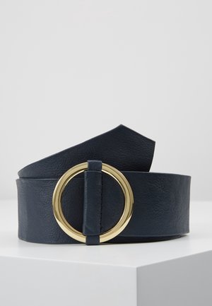 Wide black leather belt with large round gold buckle, displayed coiled on a white surface against a light gray background.