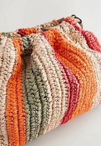 Sac bandoulière en paille tissée rayée avec des couleurs orange, vert, rouge et beige sur un fond clair.