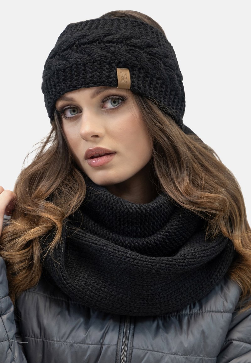 Bandeau en tricot noir avec une texture tressée et une étiquette en cuir. Associé à une épaisse écharpe noire douillette, les deux conçus pour la chaleur.