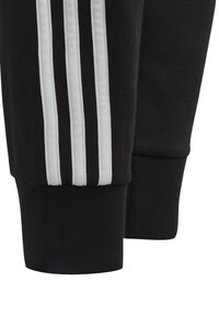 Zwarte sportbroek met een witte drie-strepen ontwerp aan de zijkanten, gemaakt van een gladde stof, met taps toelopende boorden bij de enkels.