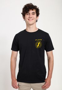 Svart t-shirt i bomull med en gul blixtgrafik och ordet "FLASH" tryckt ovanför. Klassisk passform med korta ärmar.