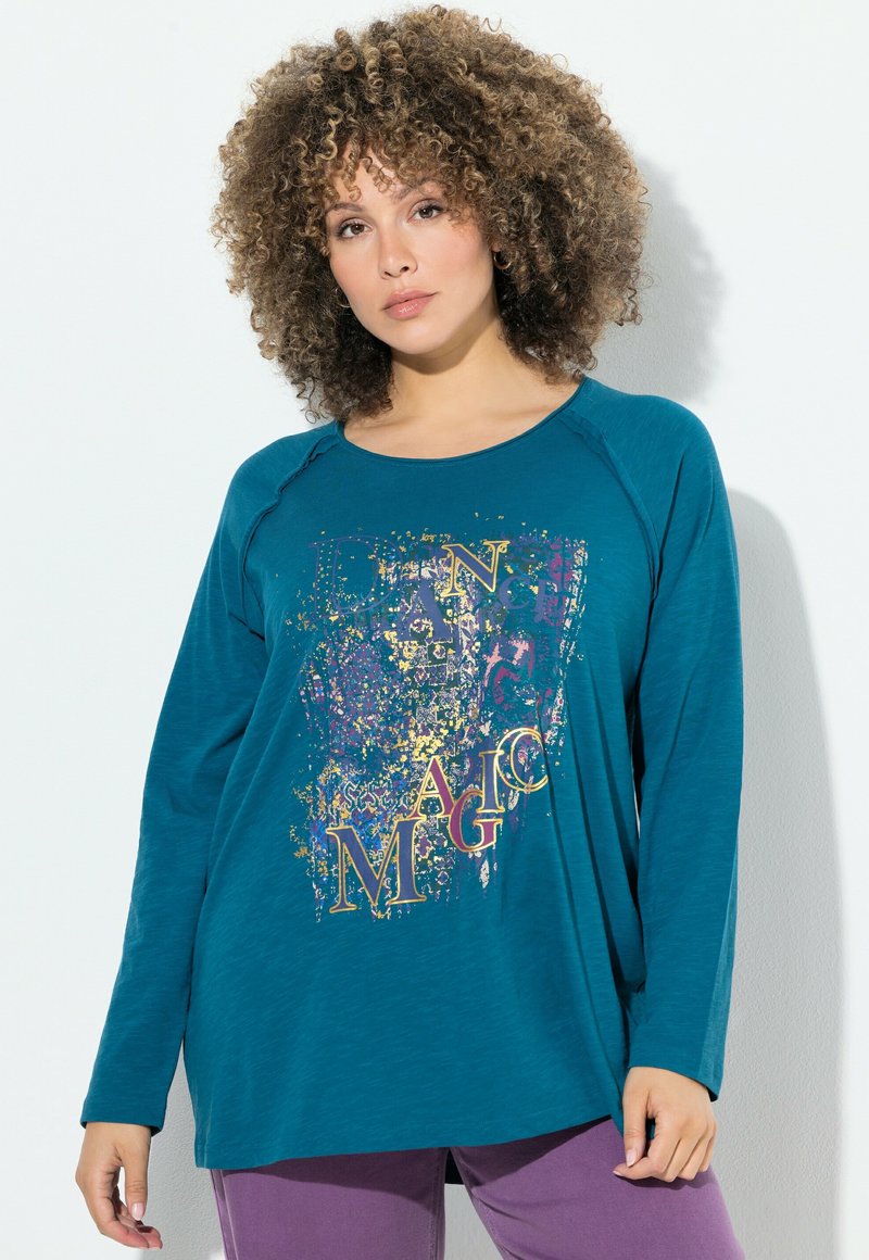 T-shirt a maniche lunghe color verde acqua con scollatura arrotondata, caratterizzato da una stampa grafica colorata con le parole "DANCE MAGIC" in accenti dorati e viola.