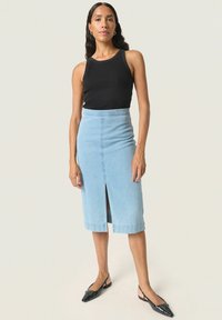 Svetlo modra denim krilna krila s sprednjim razporkom, visokim pasom, v kombinaciji s črno rebrasto majico brez rokavov in črnimi slingback čevlji.