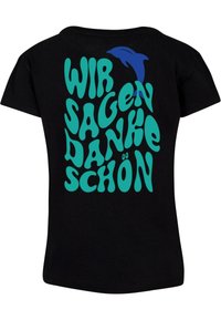 Juodas marškinėliai su turkio spalvos banguotais rašmenimis, kuriuose užrašyta „WIR SAGEN DANKE SCHÖN“, ir maža mėlyna delfino grafika.
