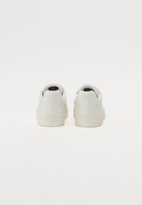 White leather sneakers with a smooth finish, rounded toe, and cushioned heel. Features minimal stitching and a pale rubber sole.