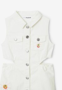 Valkoinen denim-yhtenäinen asu kauluksilla, hopeanvärisillä napituslippuilla, kahdella rintataskulla ja brodeeratuilla yksityiskohdilla, joissa on kaktuskuvio.