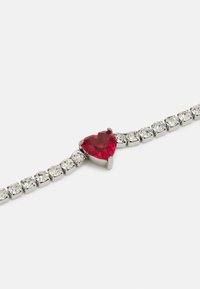 Silberarmband mit einem roten herzförmigen Stein, akzentuiert mit klaren, runden Kristallen in einem eleganten, minimalistischen Design.