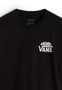 Camiseta de algodón negra con un gráfico blanco de un tigre y el logo de "VANS" en el lado izquierdo del pecho, con un diseño de cuello redondo de ajuste clásico.