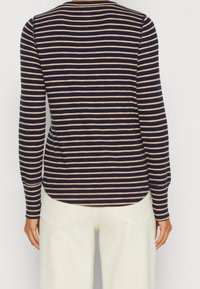 Granatowo-beżowa bluzka w paski z długim rękawem, o okrągłym dekolcie, miękkiej fakturze i dopasowanym kroju; zaokrąglony dół z tyłu.