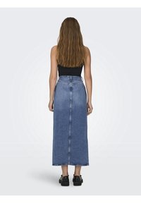 Denim maxikjol i ljusblått med rak skärning, hög midja och bakfickor. Stylar med en svart topp och svarta skor. Slät textur.