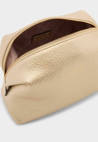 Borsa in pelle color oro con texture a granuli e chiusura con zip. L'interno è foderato in tessuto liscio con marchio.