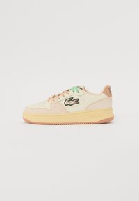 Sneakers Lacoste con accenti crema e pastello, materiali in pelle e gomma, punta rotonda, logo ricamato e suola a contrasto.