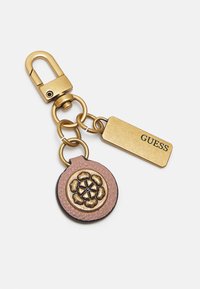Portachiavi in metallo dorato con un charm rotondo in pelle rosa decorato con un motivo floreale e un'etichetta rettangolare dorata incisa con la scritta "GUESS."