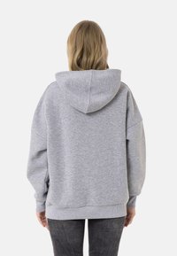 Graue oversized Kapuzenpullover mit Kordelzugkapuze, weichem Material und gerippten Bündchen und Saum. Keine sichtbaren Muster, schlichtes Design.