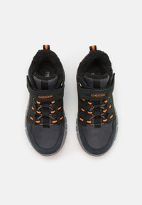 Scarpe da atletica nere e grigie con una tomaia in materiale sintetico, dotate di accenti arancioni, lacci texturizzati e un interno imbottito.