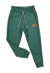 Groene joggingbroek met een elastische tailleband, voorzien van een trekkoord en twee zijzakken. Een bruine patchdetail is aanwezig op het linkerpoot.