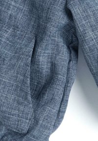 Tela azul texturizada con un patrón tejido, que presenta variaciones sutiles en el tono y un aspecto ligeramente arrugado.