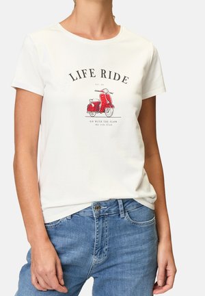 Mujer con camiseta blanca con gráfico rojo de scooter y texto "LIFE RIDE" y jeans azules, de pie frente a un fondo liso.