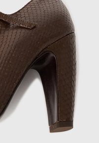 Bruine pumps van gestructureerd materiaal met een reptielpatroon. Voorzien van een slanke, glanzende hak en een afgeronde neus.