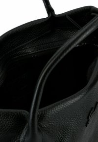 Bolso tote de cuero negro con una superficie texturizada, lados suaves, asas dobles y un bolsillo interior con cremallera para un almacenamiento seguro.