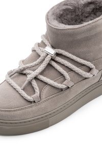 Grau Wildleder High-Top-Sneaker mit geflochtenen Schnürsenkeln und silbernen Hardware-Akzenten, ausgestattet mit einem weichen Innenfutter und einer strukturierten Sohle.