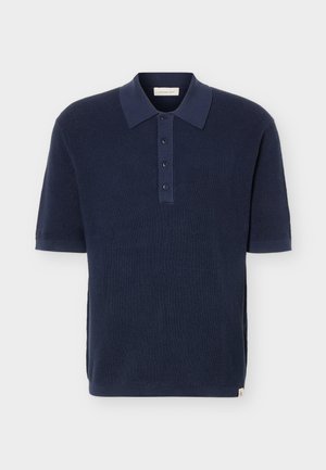 Polo in maglia a maniche corte di colore blu navy con colletto e patta con quattro bottoni, texture a nido d'ape e piccola etichetta del marchio all'orlo.