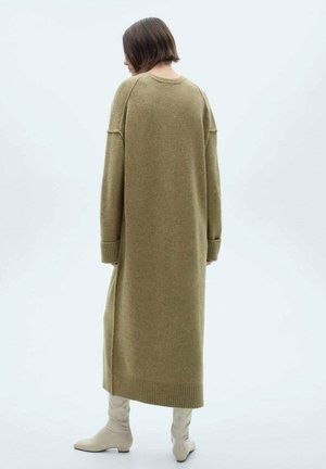 Robe tricotée longue de couleur olive, avec une coupe décontractée, des poignets et un ourlet côtelés. Le matériau semble doux et texturé, atteignant en dessous des genoux.