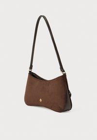 Καφέ τσάντα ώμου από σουέντ με καμπυλωτό σχήμα, έναν δερμάτινο ιμάντα και χρυσή λεπτομέρεια λογότυπου σε σχήμα διαμαντιού μπροστά. Ομαλή υφή.