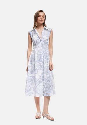 Valkoinen mekko sinisellä paisley-kuviolla, V-pääntie, kauluksellinen muotoilu, hihaton, vyötäisiltä tiukka ja hulmuava hame. Yhdistetty vaaleansävyisiin kenkiin.