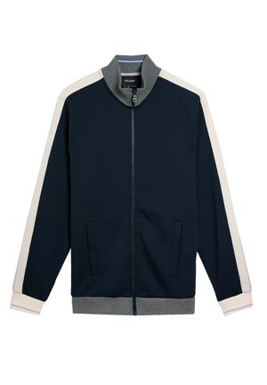 Giacca a zip blu marina con colletto e polsini grigi, strisce laterali color crema, due tasche frontali e una texture di tessuto morbida. Design atletico classico.
