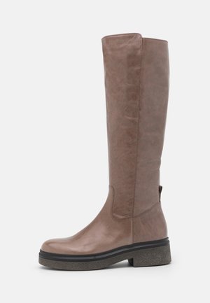 Botte haute en cuir marron avec semelle noire épaisse et petit talon carré, vue de côté sur fond blanc.